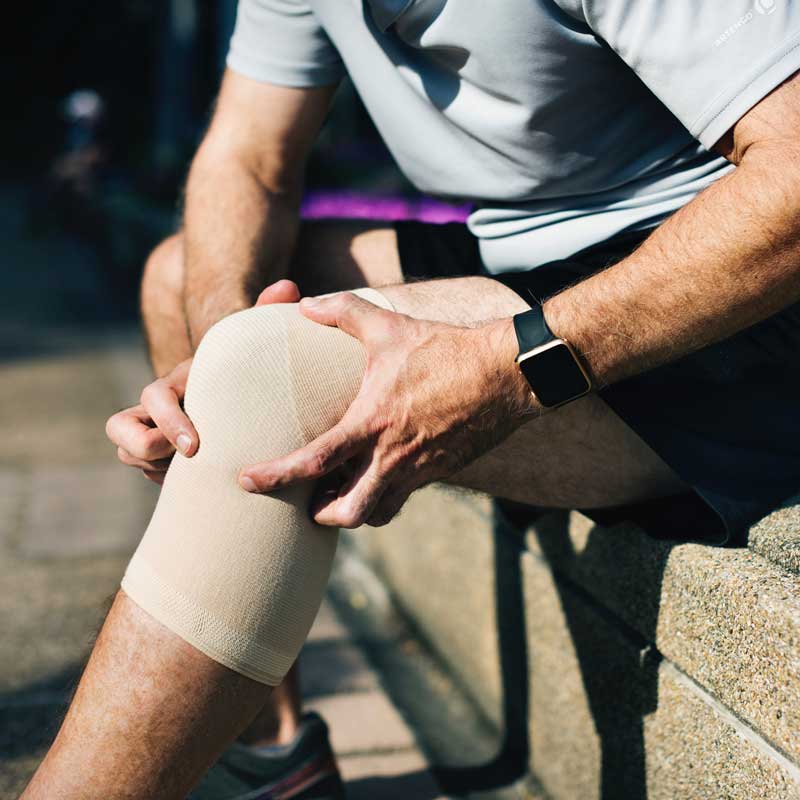 sitzender Mann mit Knie-Bandage